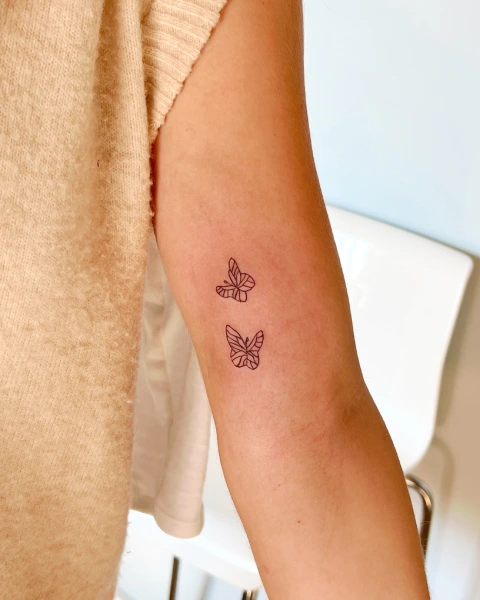 A woman with two butterflies on her arm.