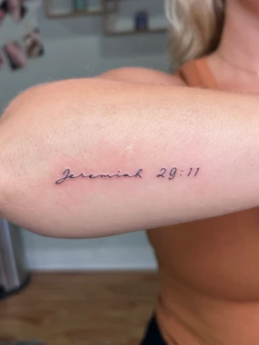 A woman with her arm that has the word jeremiah written on it.