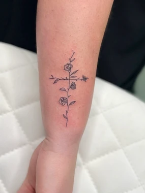 A tattoo of a cross with flowers on it.