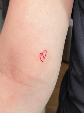 A red heart tattoo is shown on the arm.