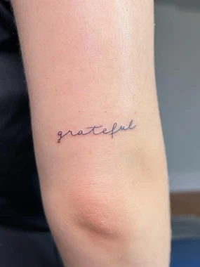 A small tattoo of the word " grateful ".