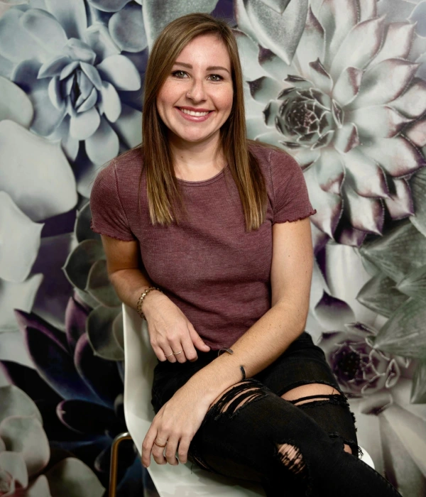 A woman sitting on top of a chair in front of a wall.