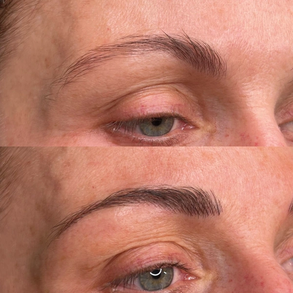 A woman with blue eyes and brown hair is getting her brows tattooed.