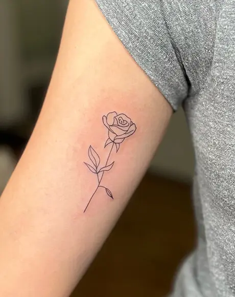 A rose tattoo is shown on the arm of someone.
