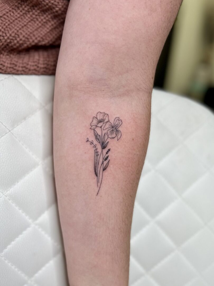 Delicate two-flower line tattoo on forearm